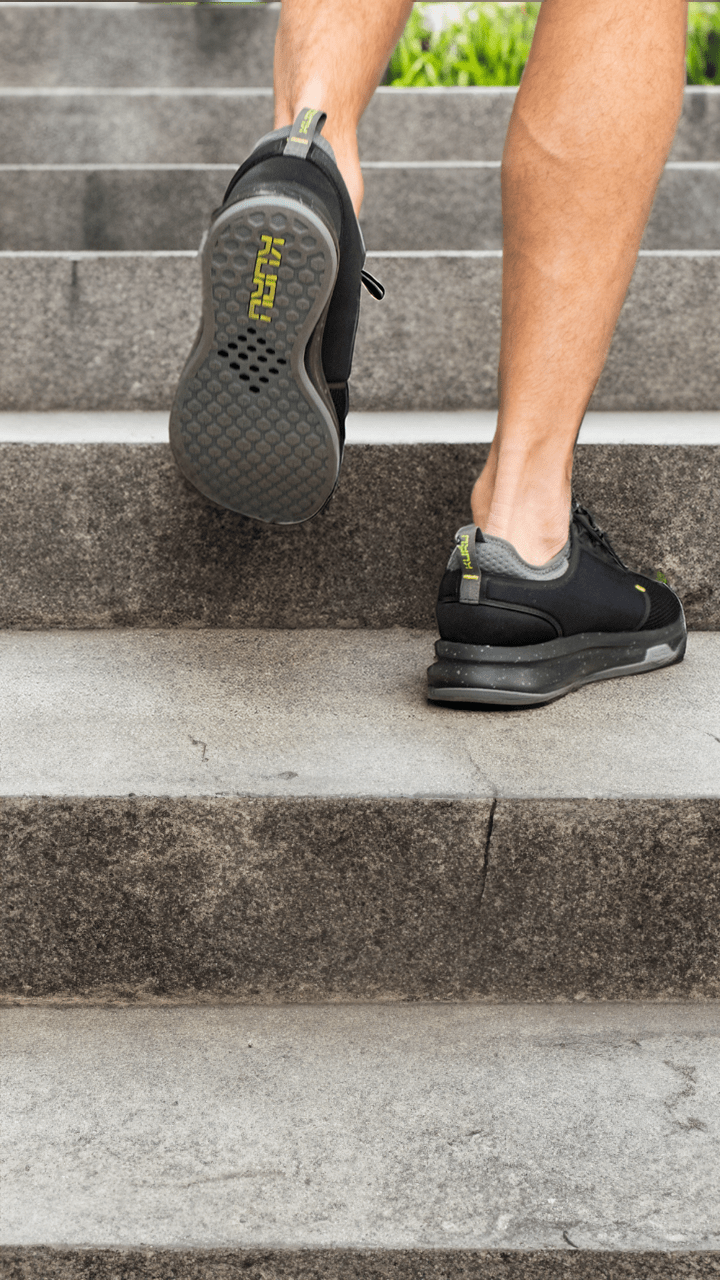 Person ascending stairs, showcasing the JetBlack ATOM by KURU Footwear.
