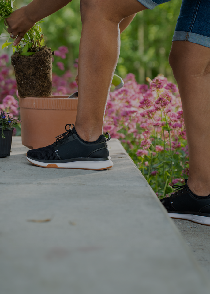 Woman wearing KURU ATOM Women's sneakers while gardening outdoors.