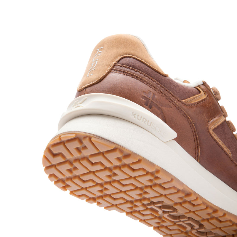 Close-up of the KuruSole and gum outsole on the KURU APOGEE Luxe Unisex Leather Sneaker in Cognac Brown.

