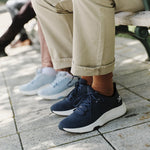 Man wearing KURU ATOM 2 Men's Athletic Sneaker in Night Blue seated on a park bench.