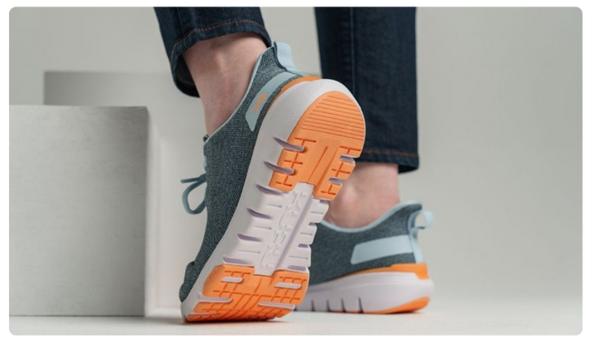 Person wearing KURU FLEX Via Women's Sneaker in Teal-Orange, showcasing the flexible outsole.