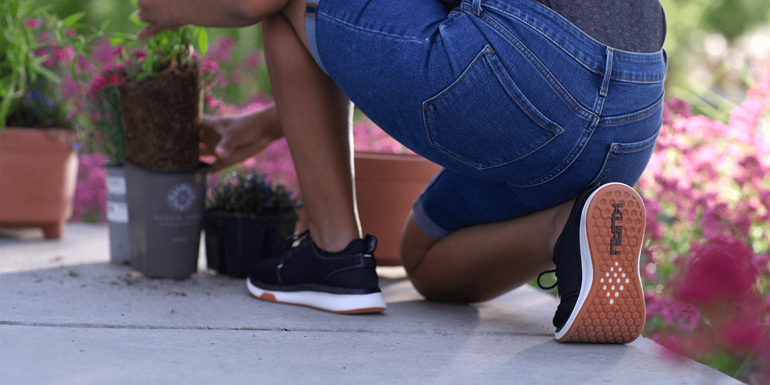 Person gardening while wearing KURU sneakers, illustrating everyday comfort and heel support for active lifestyles.