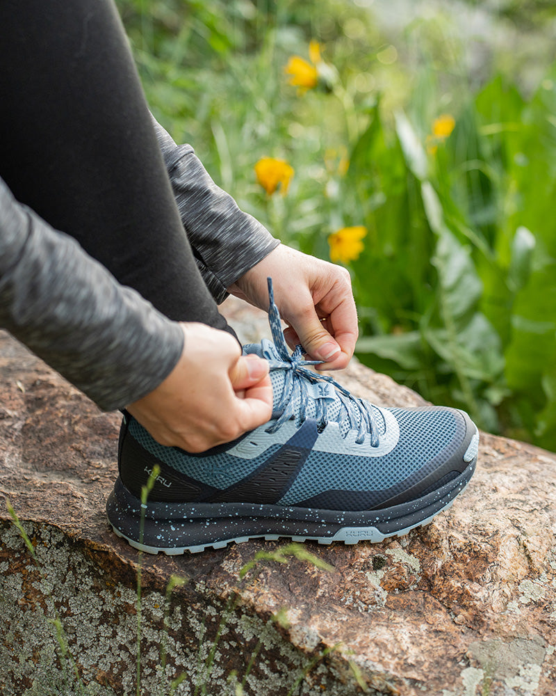Man and woman wearing KURU ATOM Trail shoes hiking at sunset on a trail.