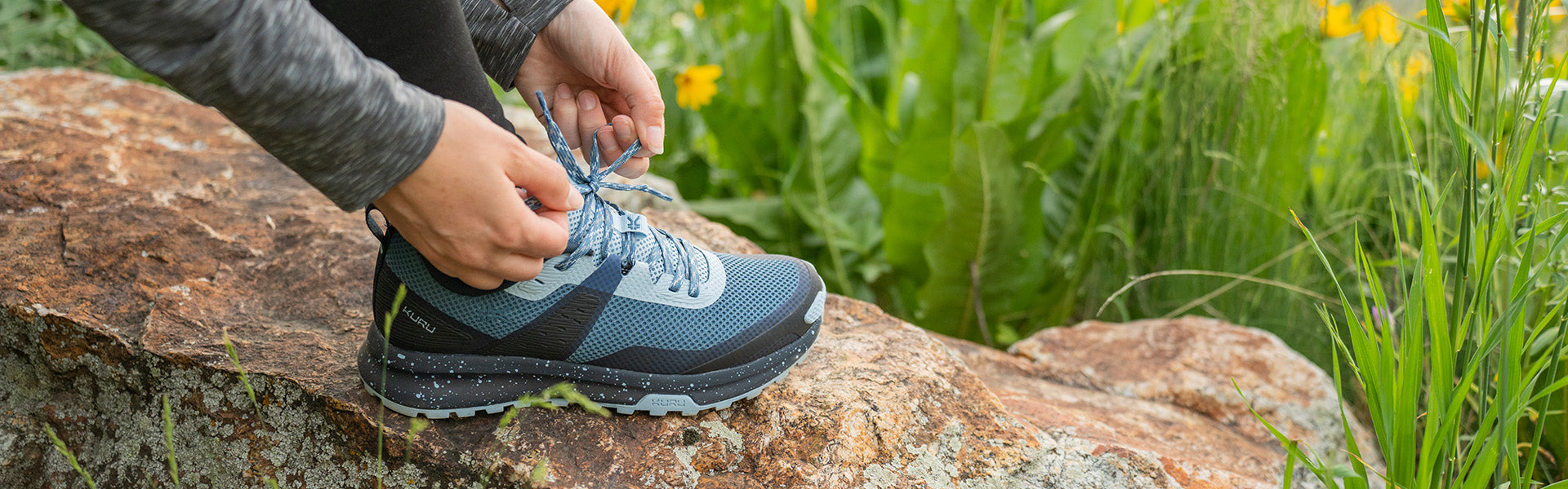 Man and woman hiking at sunset wearing KURU ATOM Trail shoes on a scenic trail.