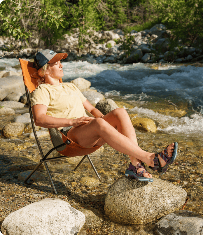Male sitting in a lawn chair next to a river