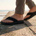 Angled profile view of the KURU MOMENT Flip Men's Flip-Flop in Jet Black.