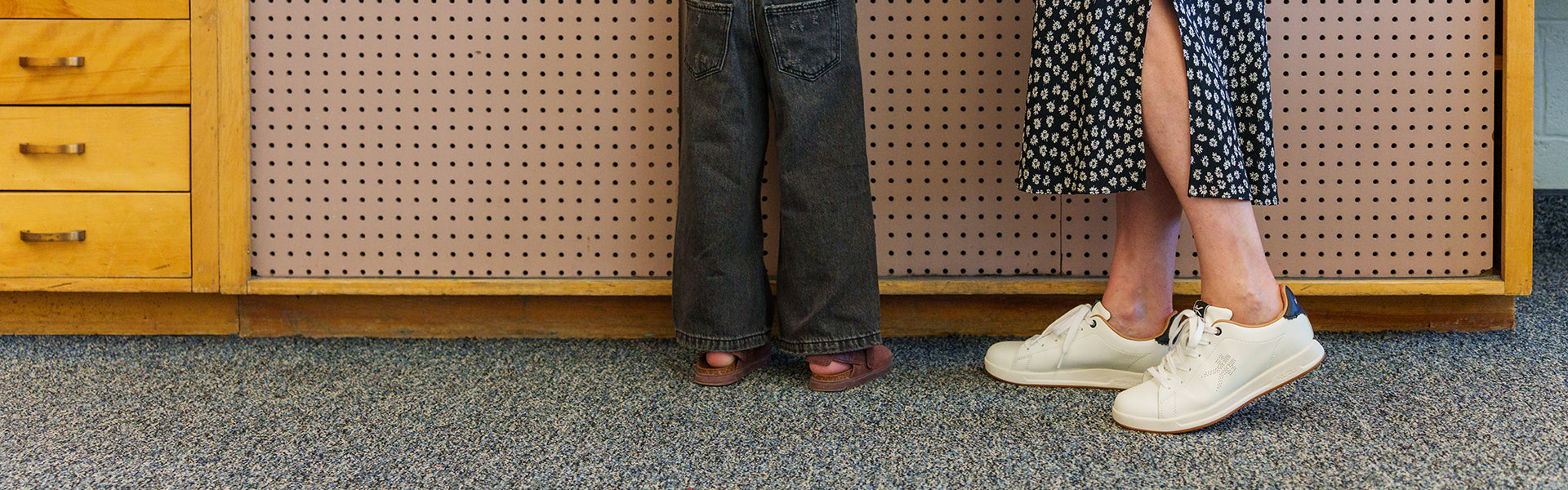 Teacher standing with a student in a classroom, wearing KURU footwear for all-day comfort on the job.