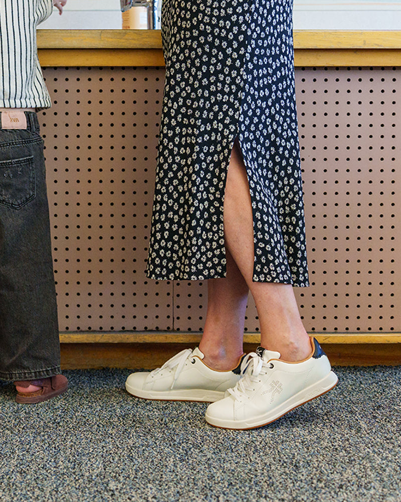 Teacher standing with a student in a classroom, wearing KURU footwear for all-day comfort on the job.