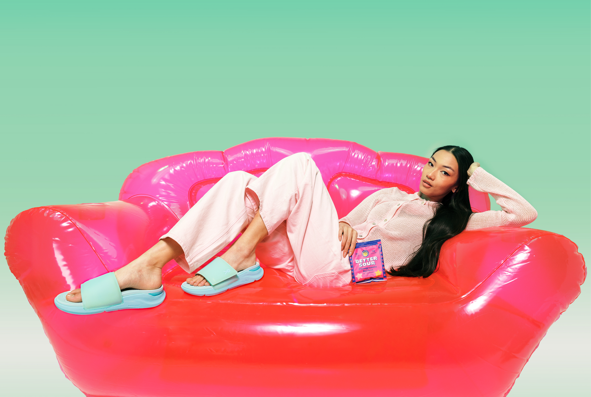 Woman wearing KURU TRIPLE MAX Ion Women's Sandals in Watermelon Slush, lounging on an inflatable couch.
