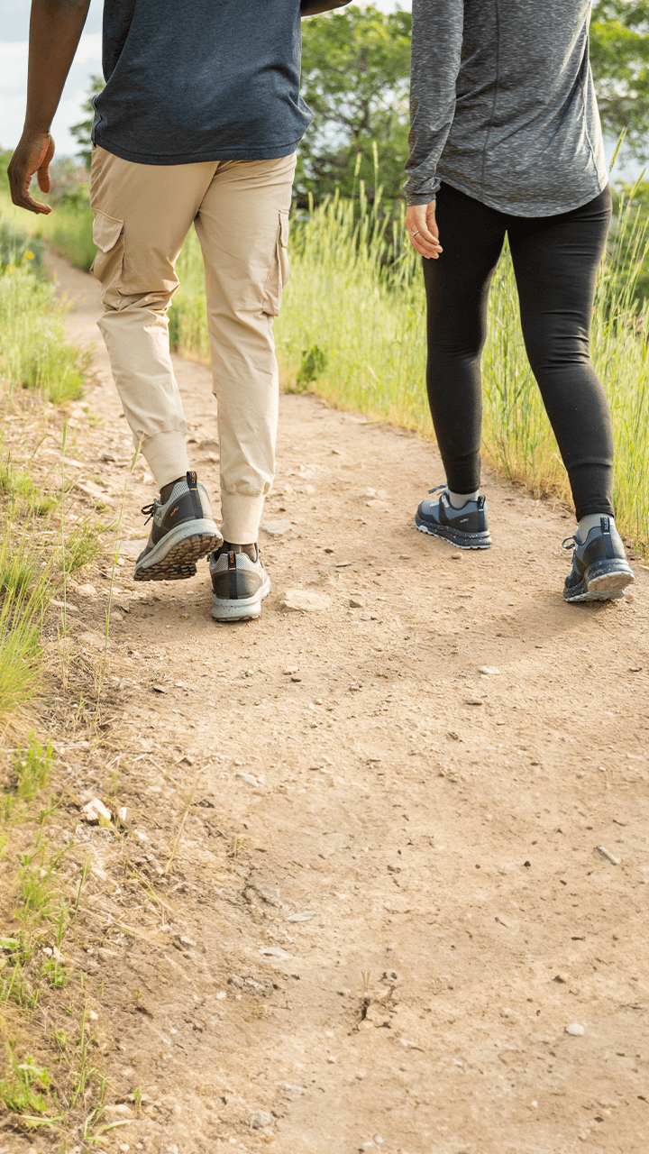 Two individuals strolling through a field, each proudly wearing their incredibly comfortable KURU Footwear shoes.