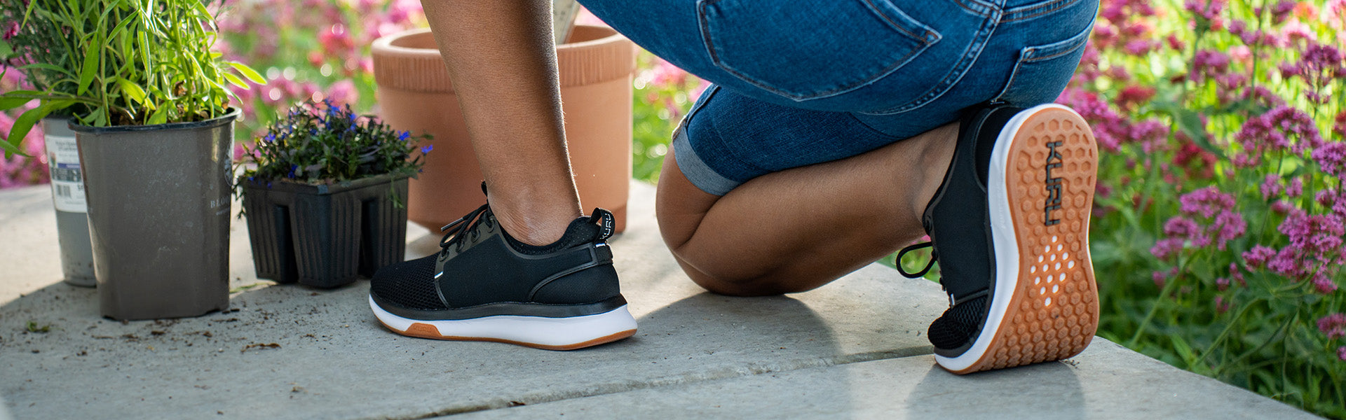 Woman wearing KURU ATOM Women's shoes in Jet Black White Gum while gardening.