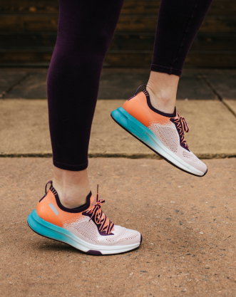 Woman working out doing high kicks, wearing KURU Footwear's FLUX shoes for alleviating foot pain